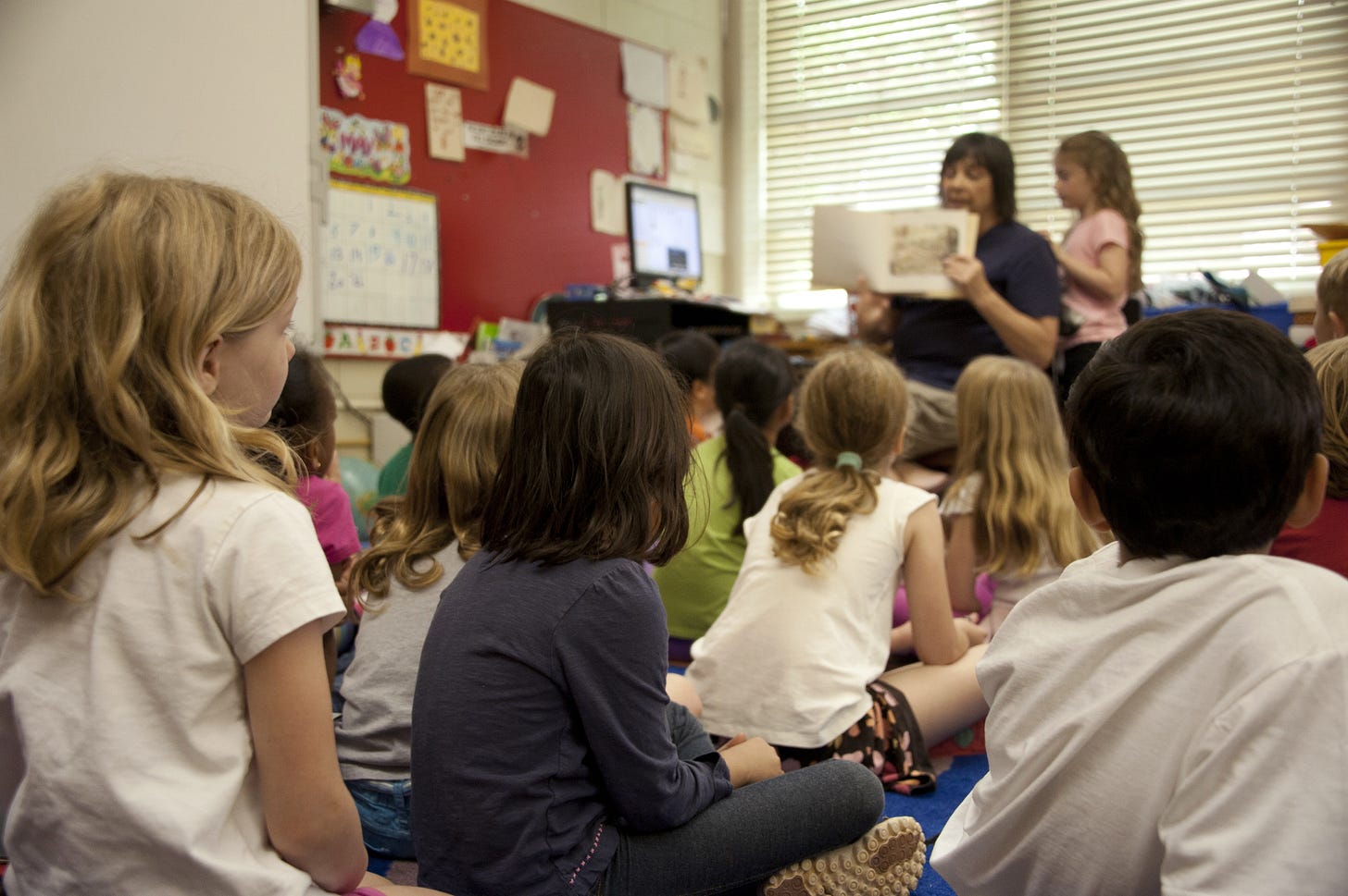 Teacher showing book pages in elementary classroom. Teacher showing book pages in elementary classroom.