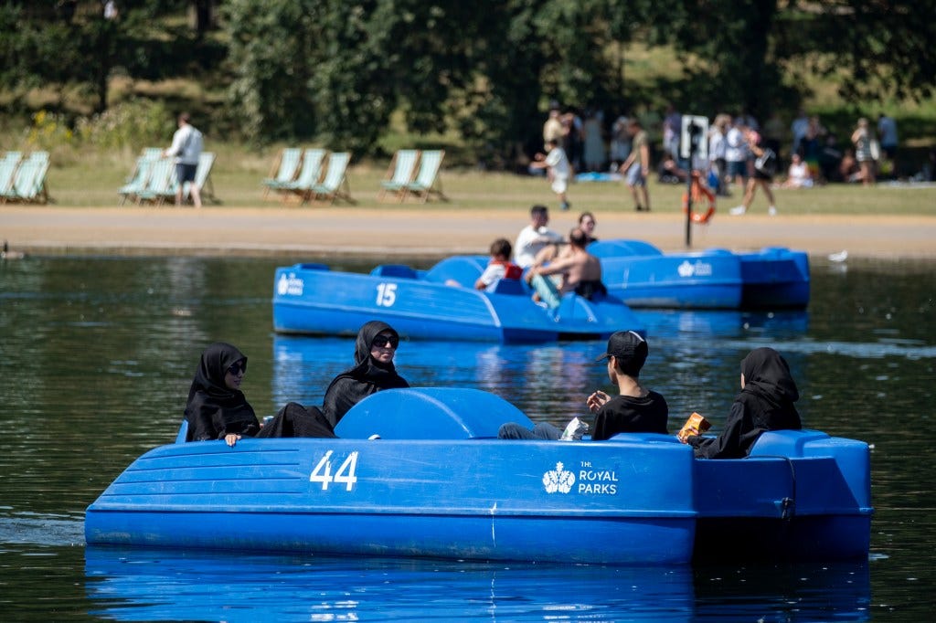 People enjoying a hot day on pedal boats in Hyde Park, London.