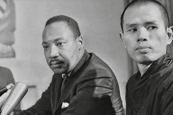 A black and white photo of Thich Nhat Hahn & Dr. Martin Luther King. They both look serious in front of microphones.