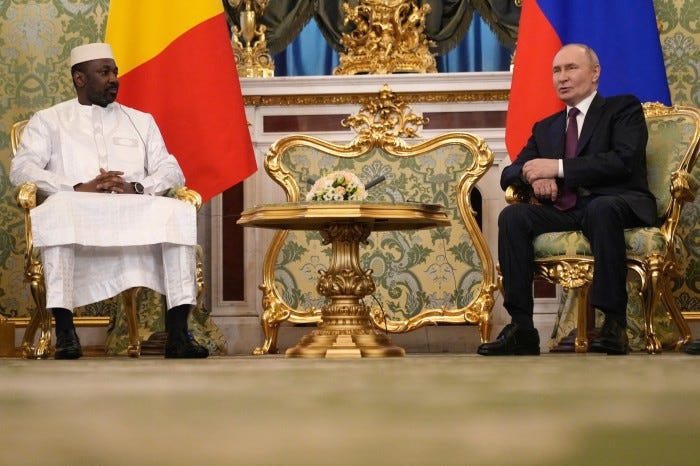 Assimi Goïta and Vladimir Putin seated facing each other in an ornate room at the Kremlin in Moscow, with Mali and Russian flags behind them.