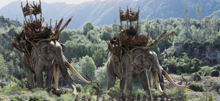 A middle eastern man in war costume, and an elephant war caravan
