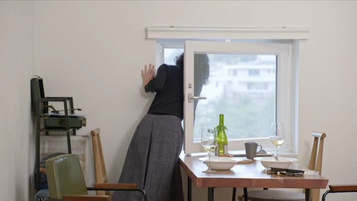 This may contain: a woman standing in front of a window next to a table