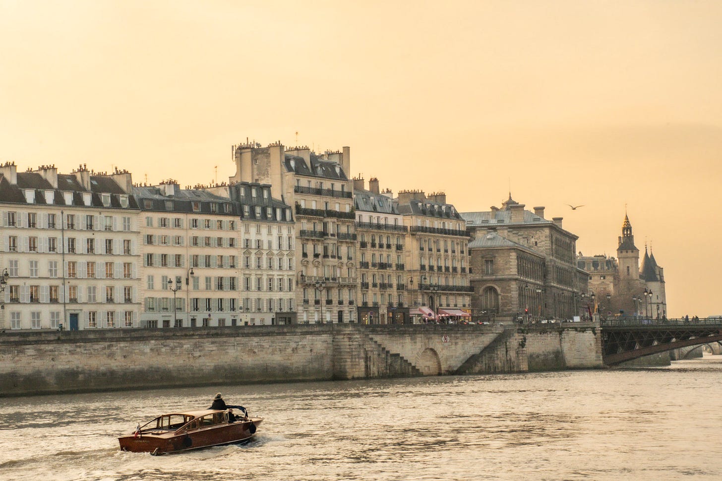 Sunset view along the Seine beside Île de la Cité with historic Paris buildings and a passing boat