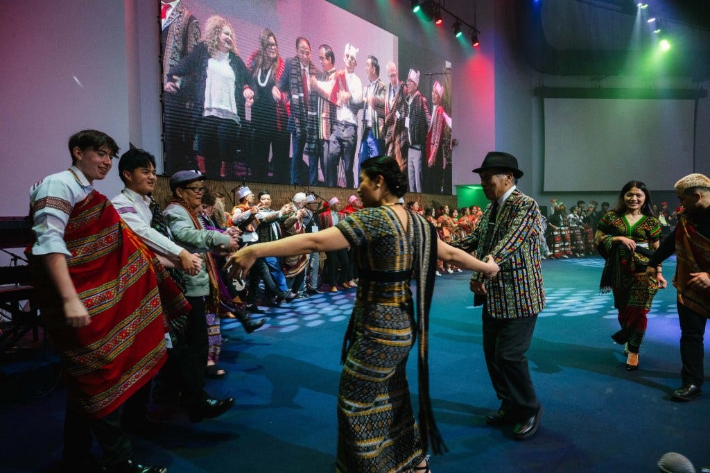 Participants of a group dance hold hands in a circle at the end of the celebration. 