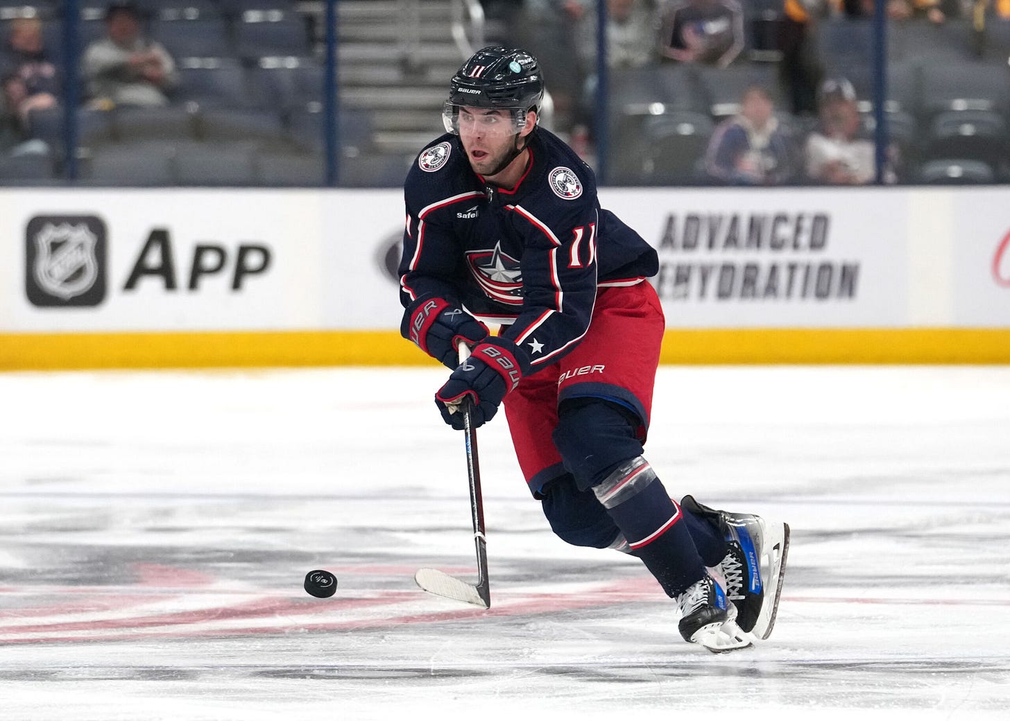 Adam Fantilli makes a pass at center ice during a game.