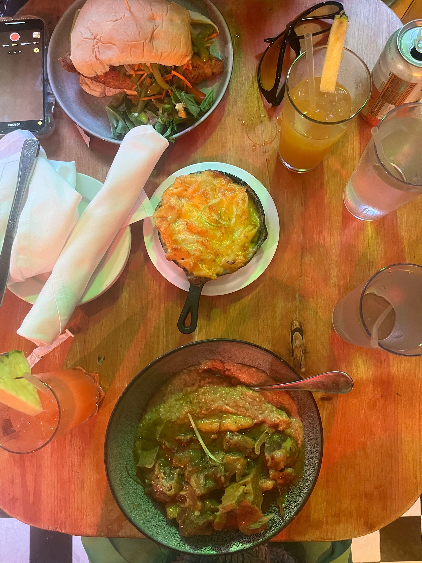 A table ar Omar's Kitchen and Rum bar with a Catfish sandwich, Oxtail and plantain grits, and Macaroni and Cheese