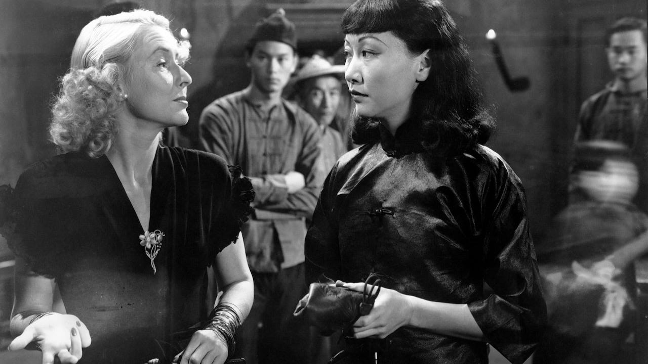 Anna May Wong in her late 30s looks suspiciously at a European/blonde woman in a scene from Lady from Chungking (1942)