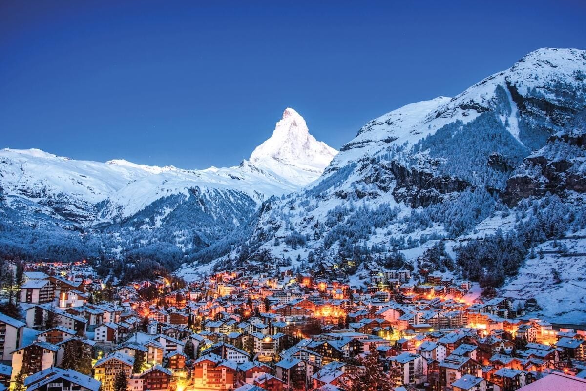 Zermatt village illuminated at dusk beneath the surrounding Alpine peaks. Zermatt village illuminated at dusk beneath the surrounding Alpine peaks.