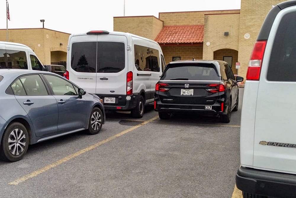 White passenger vans parked outside the Harlingen immigration court White passenger vans parked outside the Harlingen immigration court