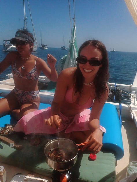 two girls cooking and eating fresh caught perch with the hands on the deck of a canoe
