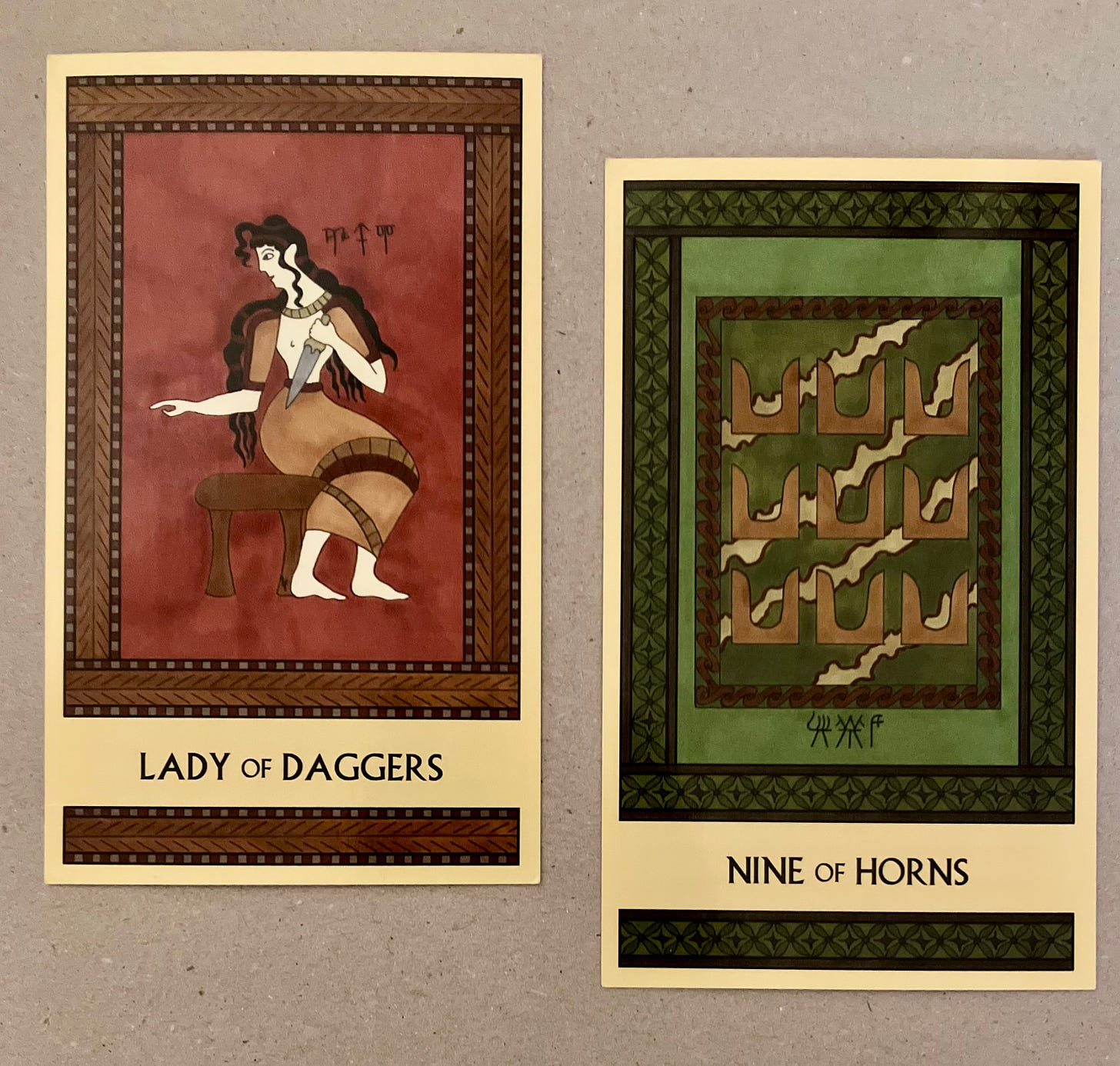 Two Minoan Tarot cards side by side on a greyish-beige background. The Lady of Daggers is painted in shades of deep red and brown. It depicts a Minoan woman seated on a stool, facing right but with her head turned back to the left. She holds a dagger in her left hand. The Nine of Horns is painted in shades of deep green and brown. It depicts a wall painting that shows nine pairs of tan colored sacred horns, in three rows of three, with a rippled multicolor background. 