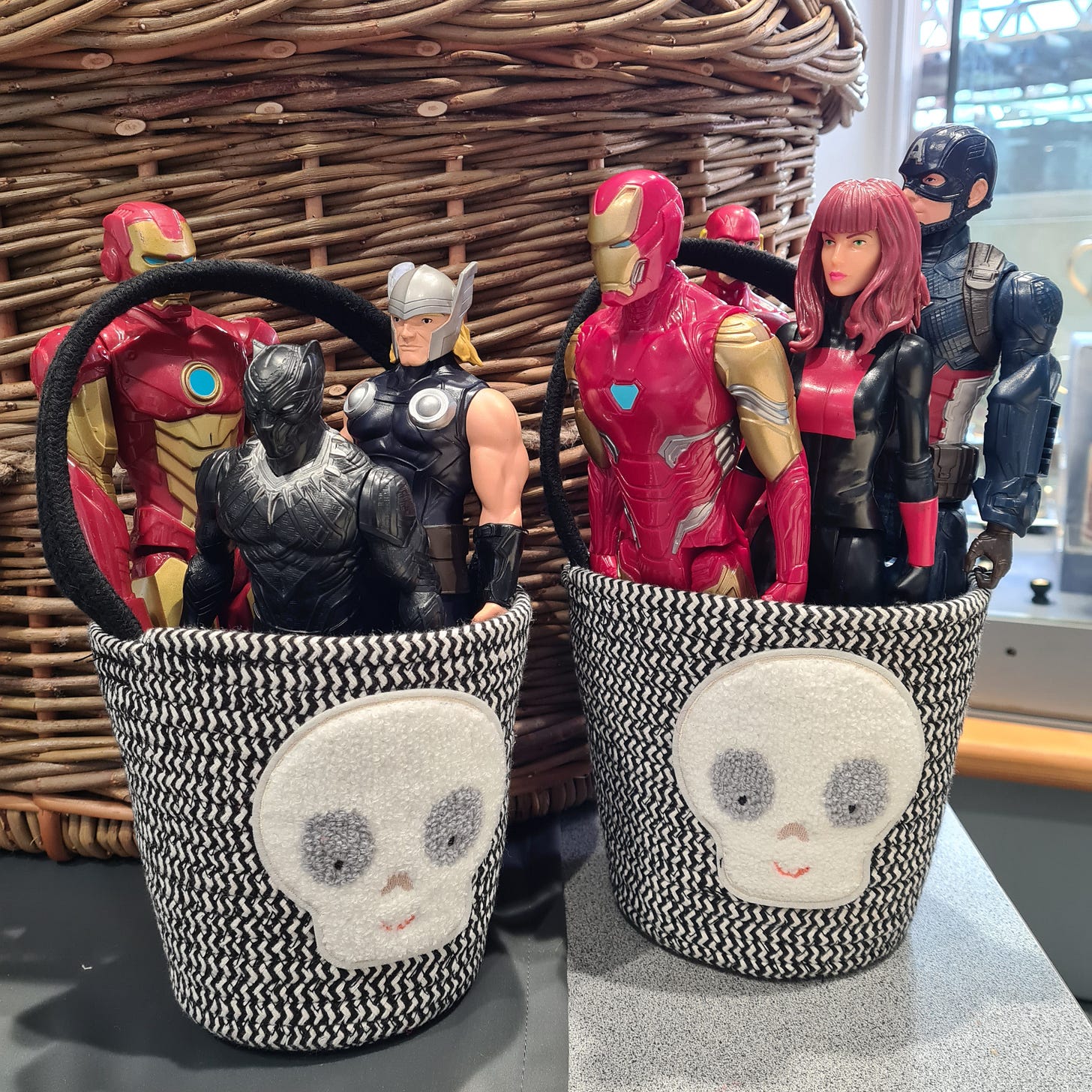 Two fabric buckets with friendly skull motifs stuffed with Marvel action figures from a charity shop.