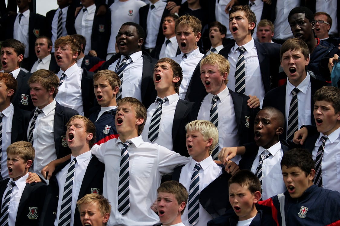Free A diverse group of schoolboys in uniforms cheering energetically outdoors. Stock Photo Free A diverse group of schoolboys in uniforms cheering energetically outdoors. Stock Photo