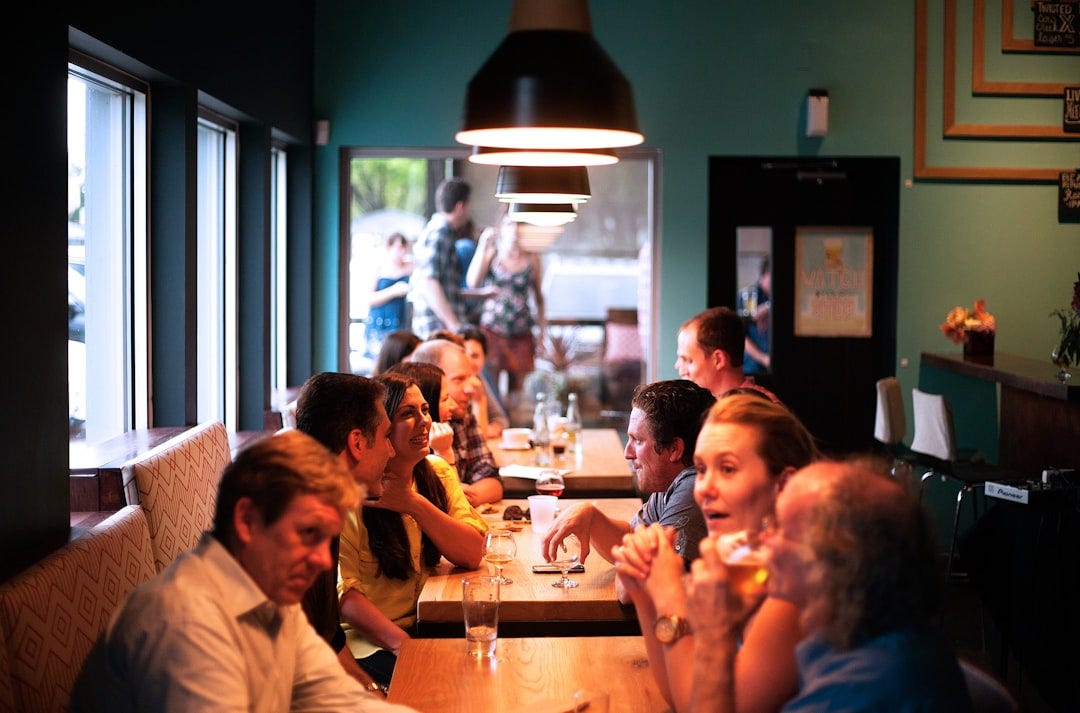people sitting beside brown wooden table inside room people sitting beside brown wooden table inside room