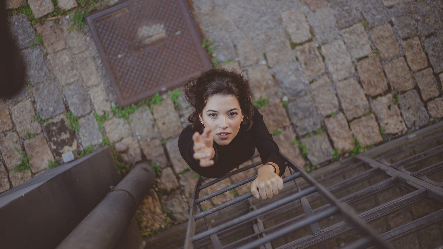 Young woman climbing metal ladder on urban building, reaching upward - representing Gen Z navigating precarious career paths and broken workplace structures