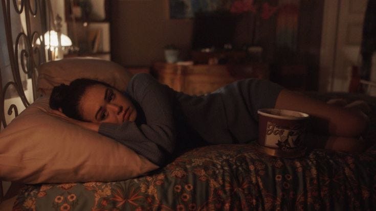 This may contain: a woman laying on top of a bed next to a lamp