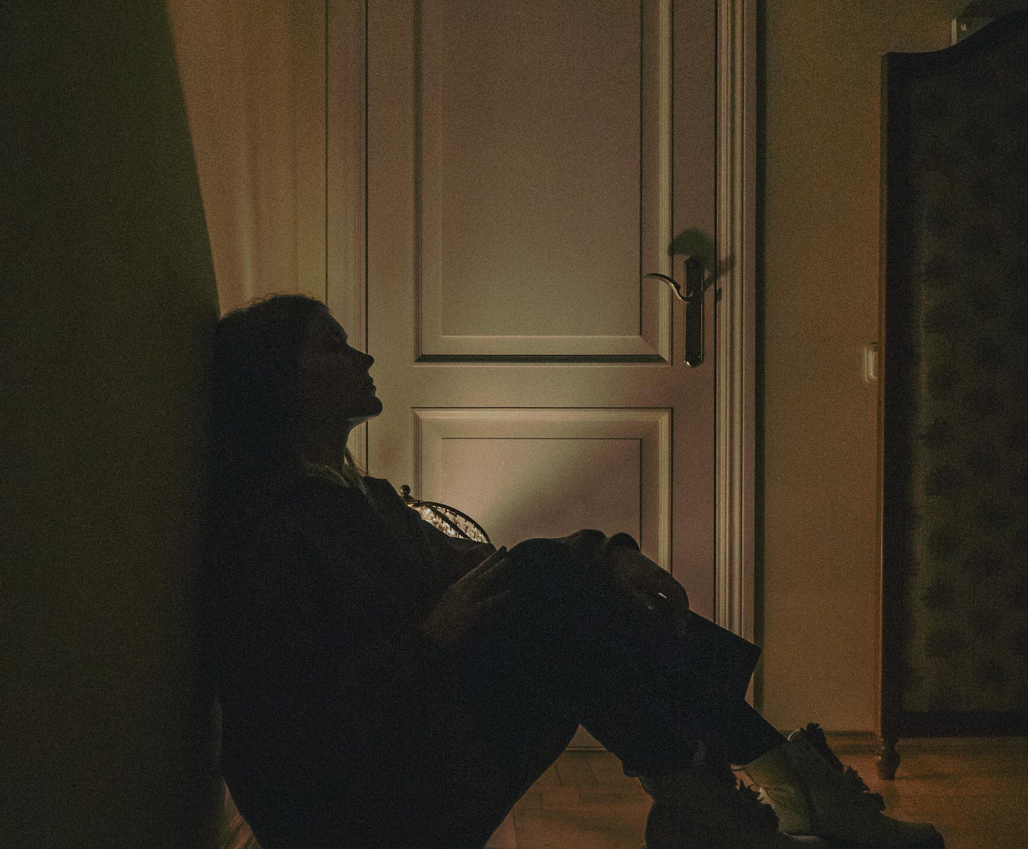 A Person Sitting on Floor Beside a Door · Free Stock Photo