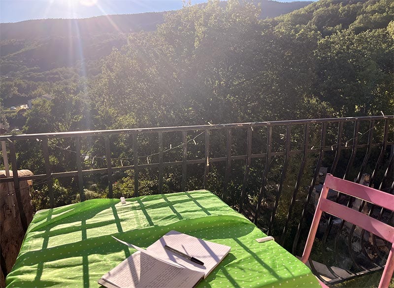 Une table, une chaise, une terrasse et une vue sur les collines environnantes. 