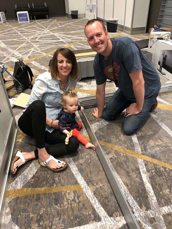 Family helping Parley set up booth at a conference. The booth backdrop is of a shark and says "Stay out of dangerous waters."