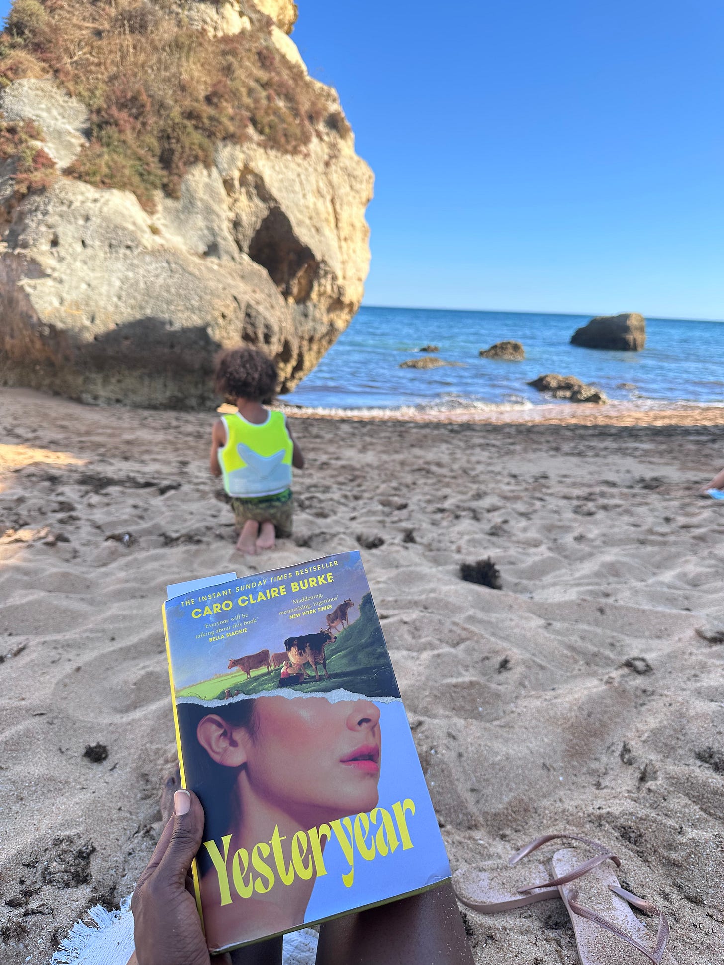 Yesteryear by Caro Claire Burke, held on the beach with a child playing in the background