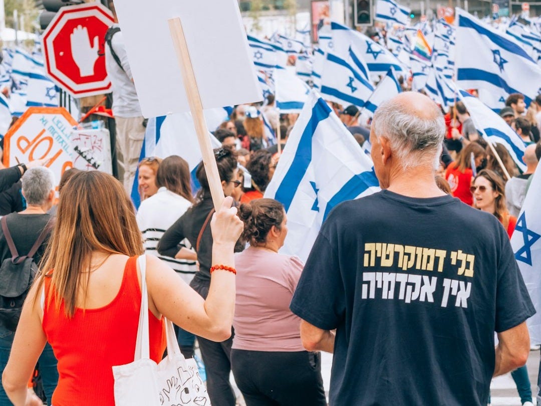 a group of people walking down a street holding signs a group of people walking down a street holding signs