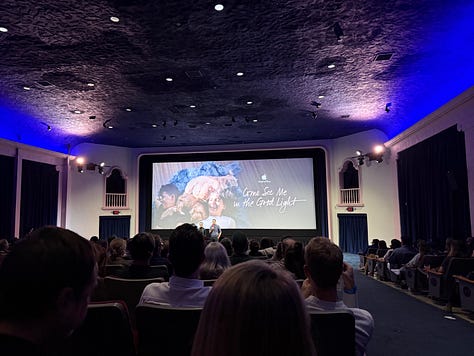 three photos of packed movie theaters screening "Come See Me in the Good Light." Giant screens with Andrea's face, or footage of Meg and Andrea hugging.