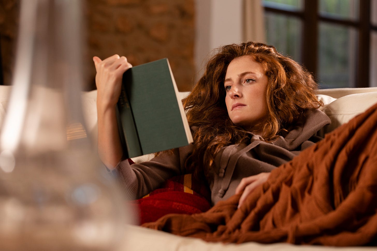 Woman reading a book while lying on the couch Woman reading a book while lying on the couch