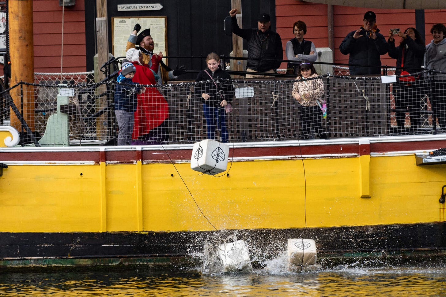 Crates splash into the Fort Point Channel after being tossed overboard by three young museum goers from the merchant vessel Eleanor during a visit to the Boston Tea Party Museum. (Jesse Costa/WBUR) Crates splash into the Fort Point Channel after being tossed overboard by three young museum goers from the merchant vessel Eleanor during a visit to the Boston Tea Party Museum. (Jesse Costa/WBUR)