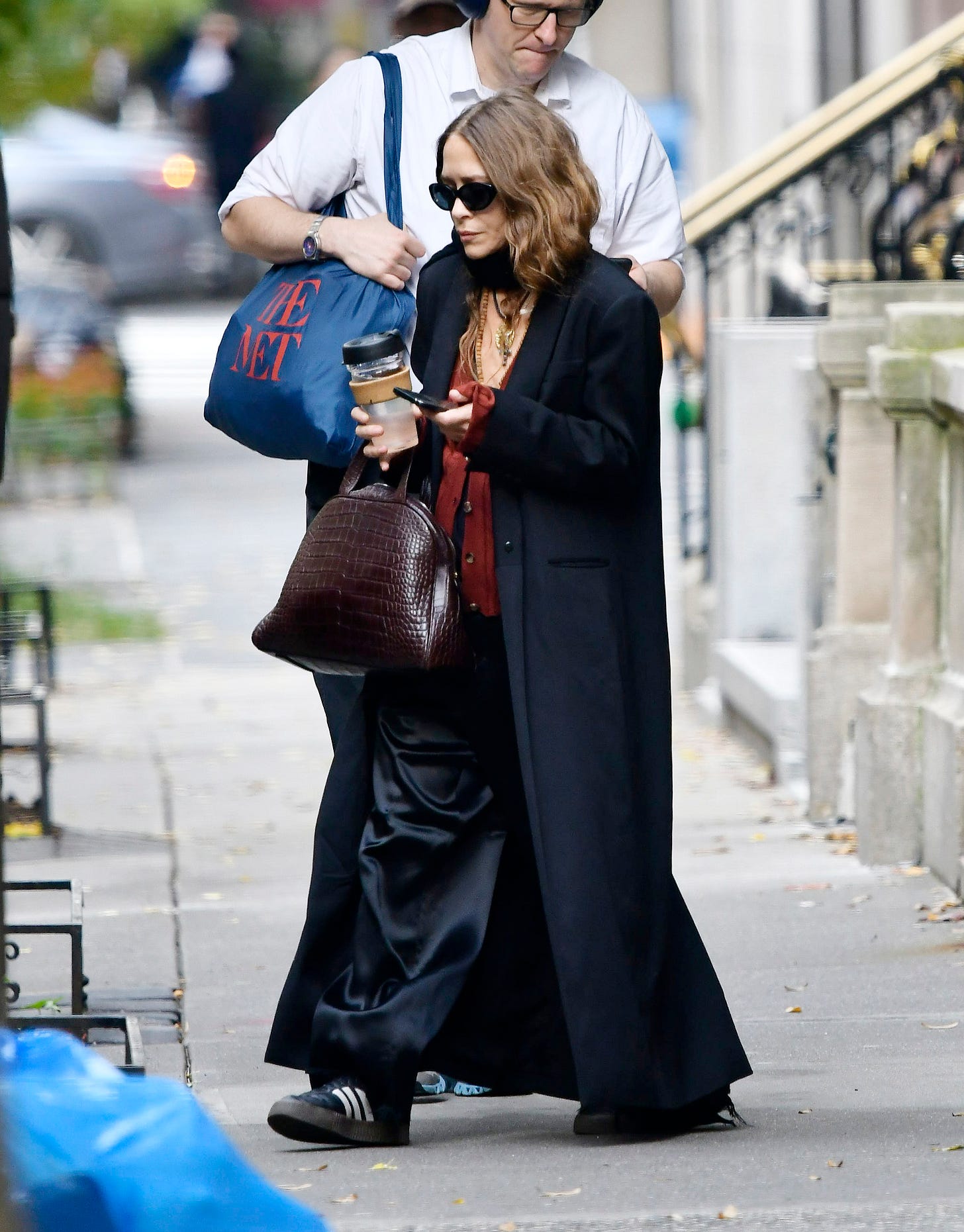 mary-kate olsen wearing a long coat with silky trousers, adidas, and a croc-embossed bag