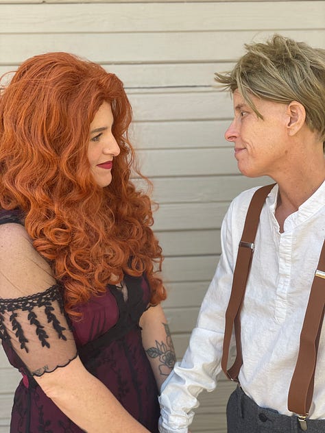 Megan Falley wears a curly red wig and maroon gown, Andrea Gibson wears a short blond wig, linen shirt and suspenders. They become Jack and Rose from Titanic, for a moment.
