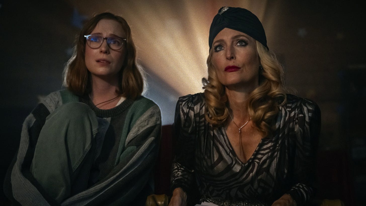 Teenage Sex and Death at Camp Miasma | Still features Hannah Einbinder as Kris and Gillian Anderson as Billy watching a movie.