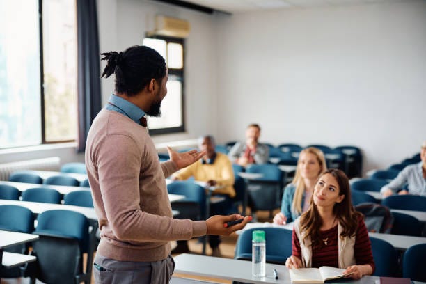 Black adult education teacher talking to group of students during a lecture in the classroom. Black adult education teacher talking to group of students during a lecture in the classroom.