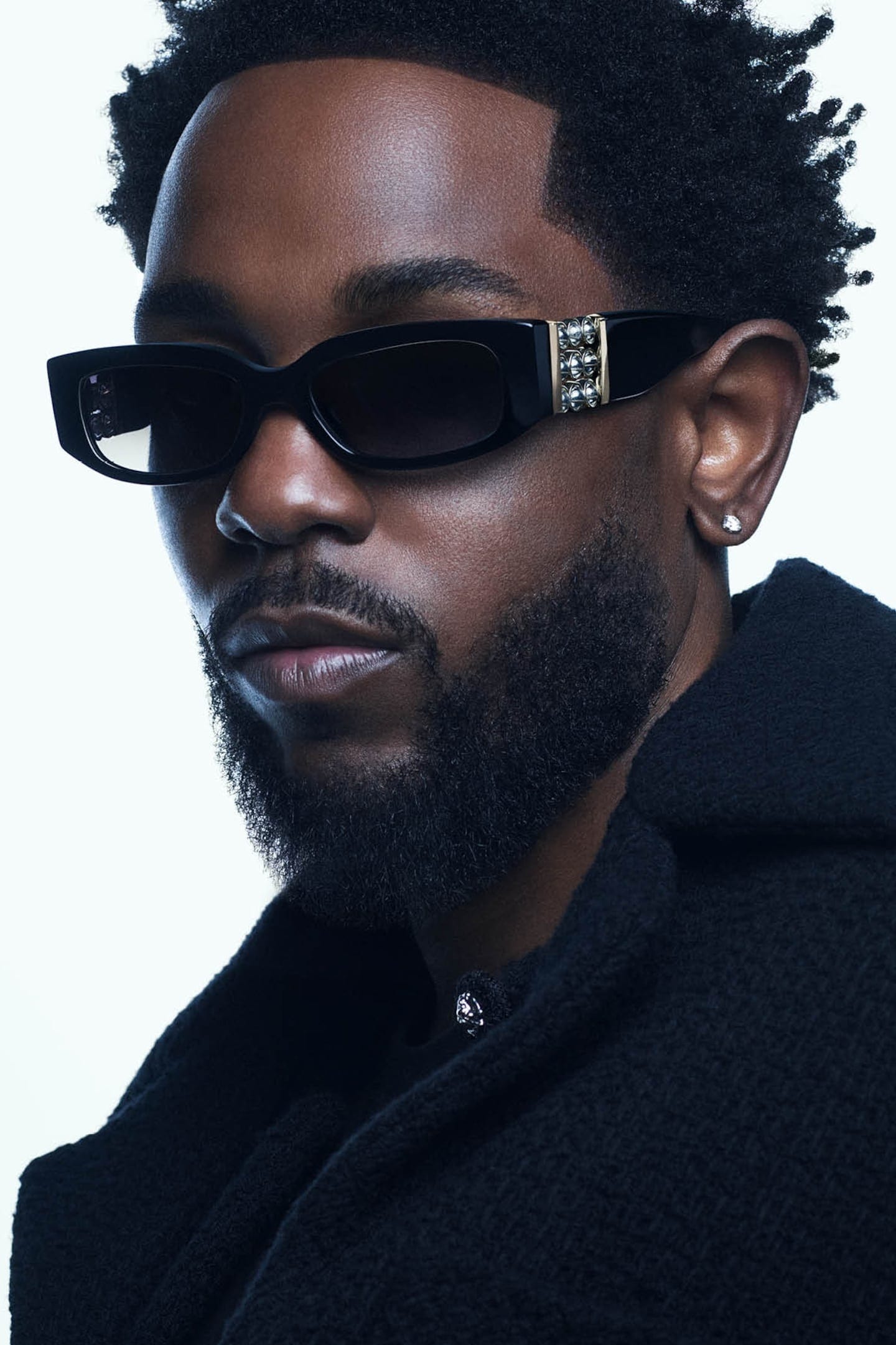 Close Kendrick Lamar headshot in black coat and black Chanel sunglasses. Close Kendrick Lamar headshot in black coat and black Chanel sunglasses.