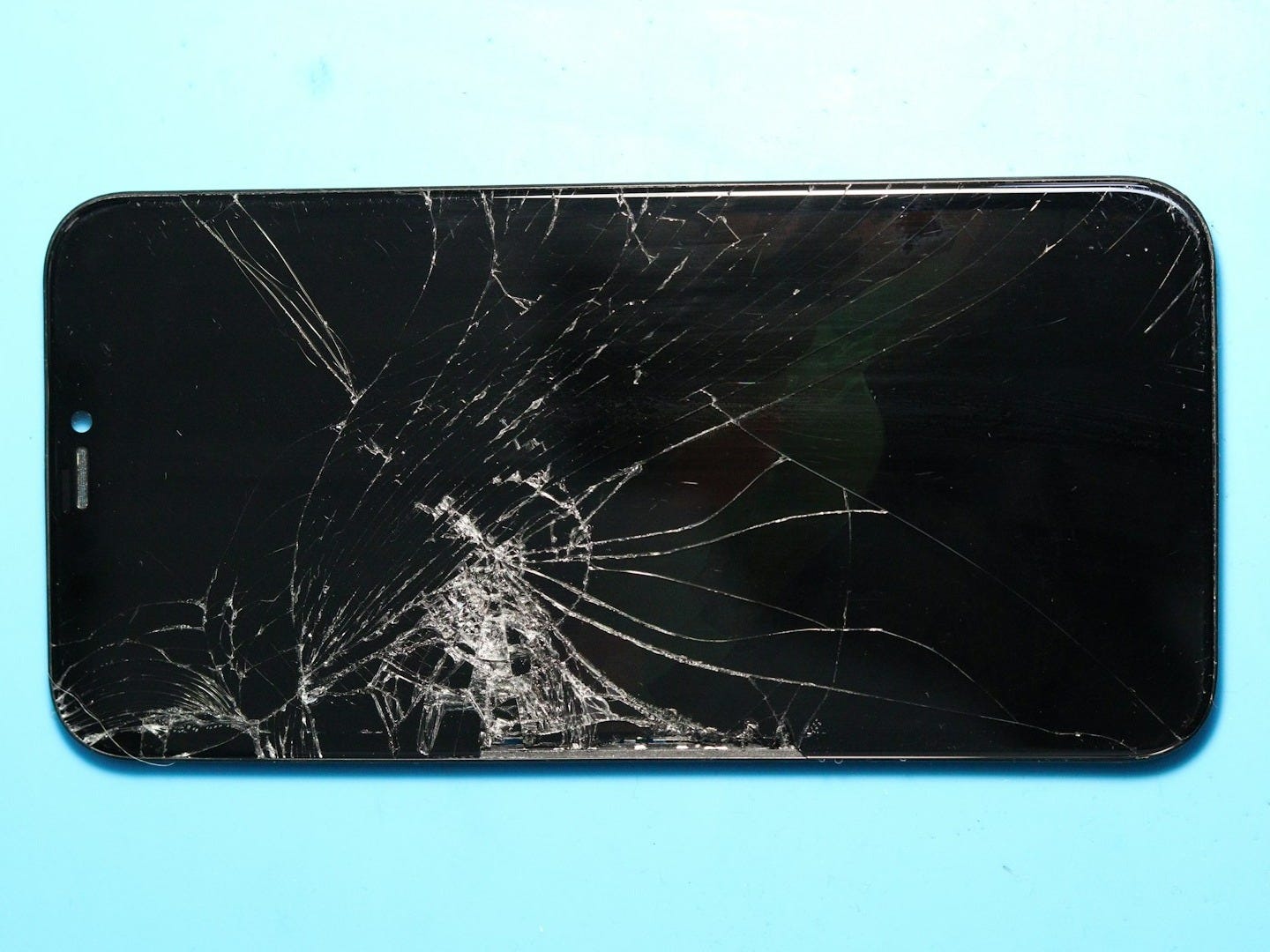 Broken smartphone screen on a blue surface. Broken smartphone screen on a blue surface.