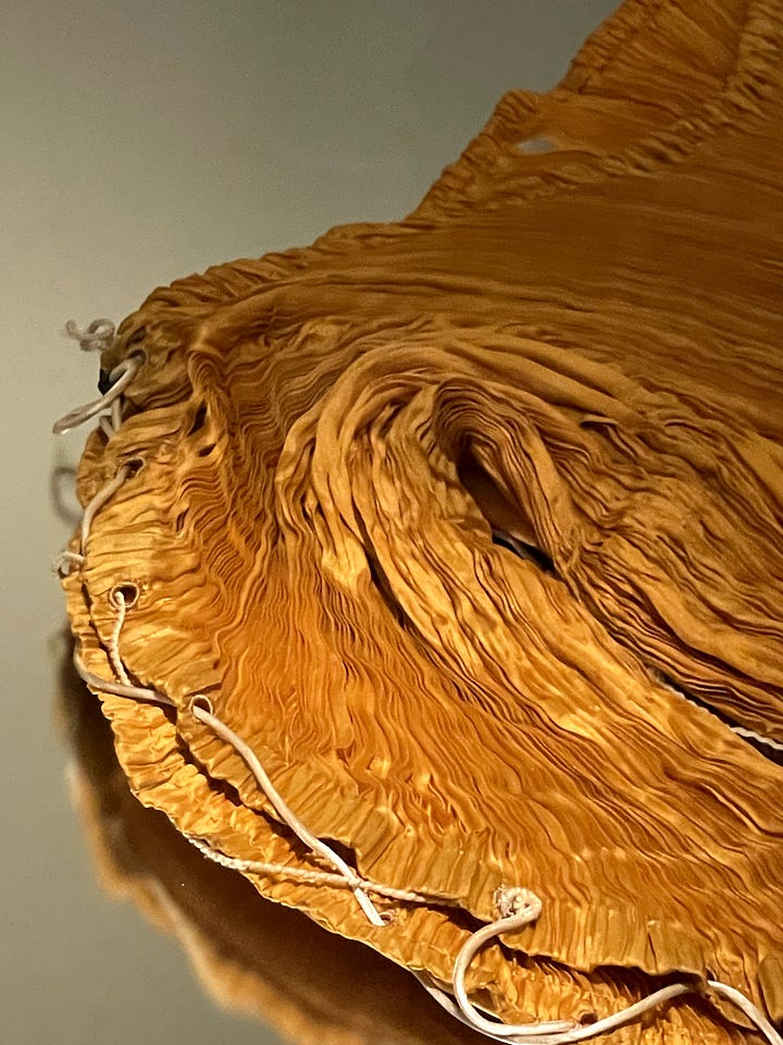 LEFT: The shoulder of a silk charmeuse dress pleated in Fortuny's signature wavy style with fine cord weaving in and out of the edges to connect the front and back body. RIGHT: The upper bodice of a gown covered in horizontally pleated chiffon over a lighter base with a sweetheart neckline and strapless silhouette.