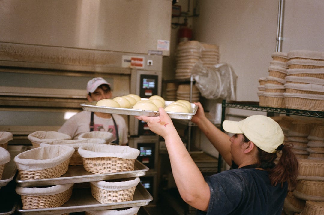 Jessica Eaton-Sicairos brings a tray of brioche rolls to the oven