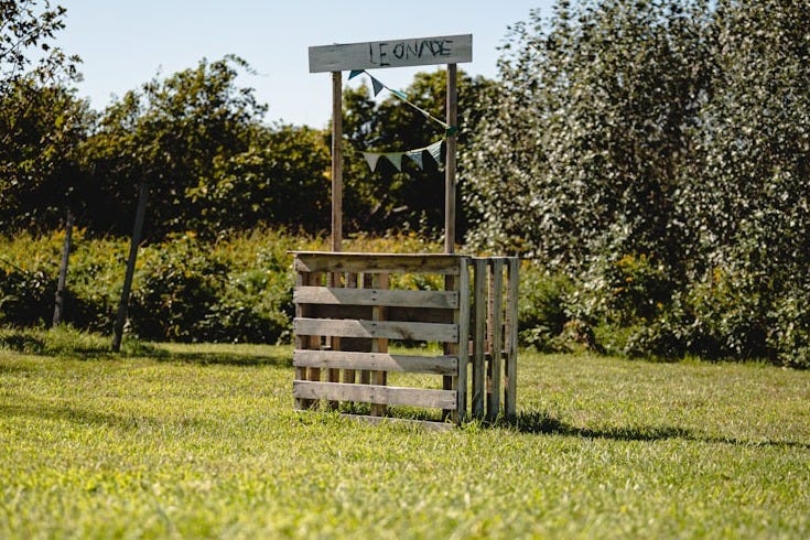 a wooden sign sitting on top of a lush green field a wooden sign sitting on top of a lush green field