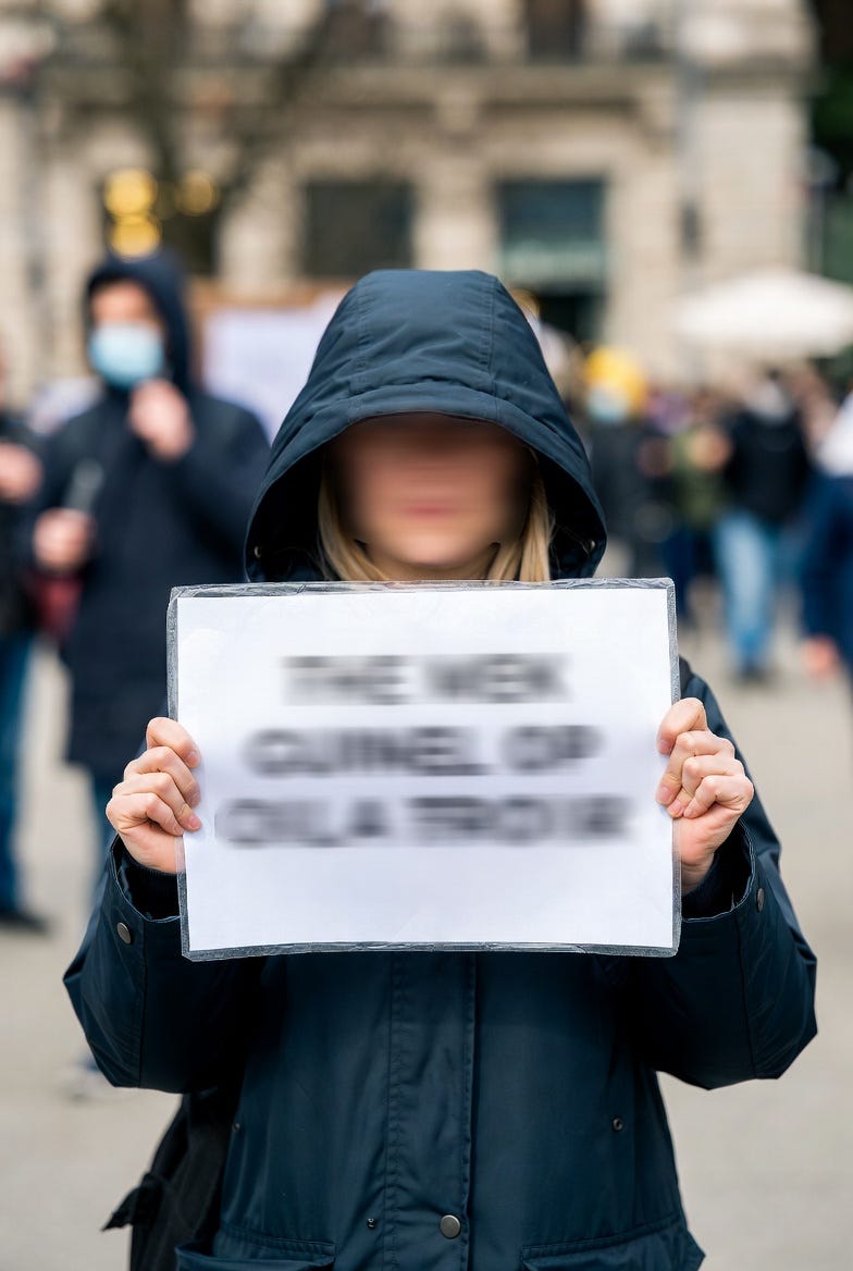 a protestor holding up a sign that is blurred out