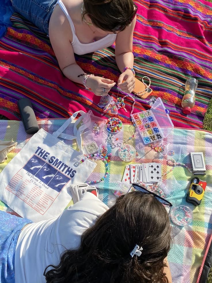 This may contain: two women laying on a blanket with various items