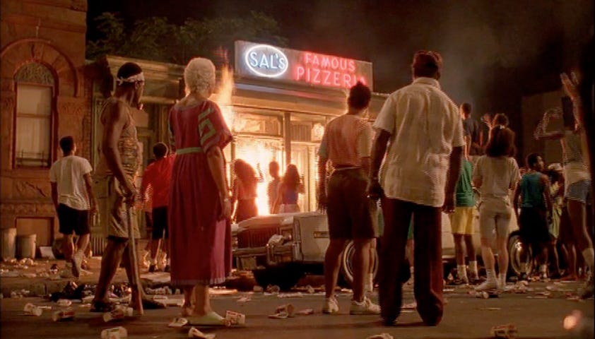 This image shows several spectators standing on the street and facing Sal's Famous Pizzeria, which is on fire, in the famous concluding sequence of Spike Lee's 1989 film Do the Right Thing. This image shows several spectators standing on the street and facing Sal's Famous Pizzeria, which is on fire, in the famous concluding sequence of Spike Lee's 1989 film Do the Right Thing.