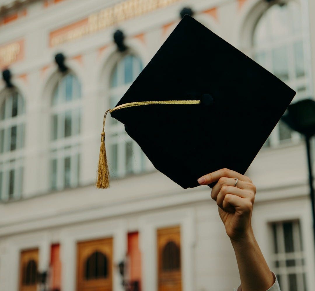 person holding black academic hat person holding black academic hat