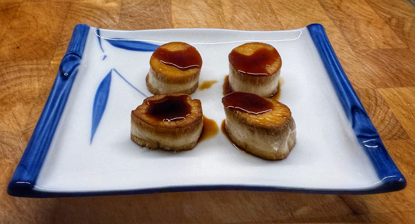 Four seared king oyster mushroom "scallops", presented on a square Japanese serving dish and topped with a brush of soy concentrate Four seared king oyster mushroom "scallops", presented on a square Japanese serving dish and topped with a brush of soy concentrate