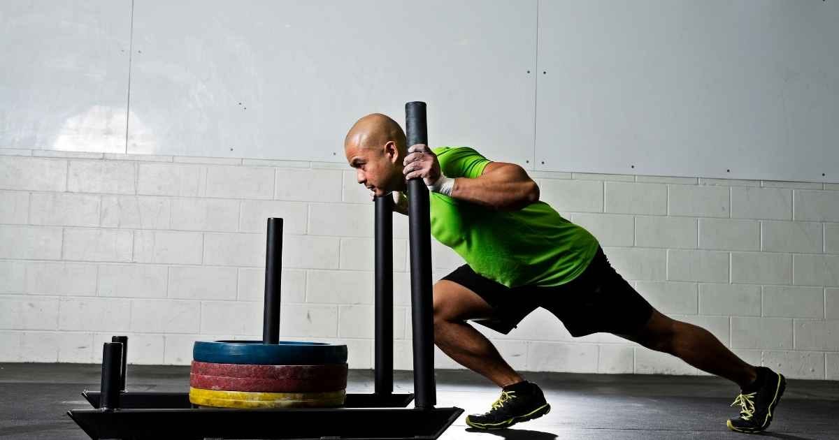 athletic man pushing a gym sled