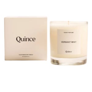 A glass vessel with a white candle inside it. Candle says Verdant Mint and Quince on it. A glass vessel with a white candle inside it. Candle says Verdant Mint and Quince on it.