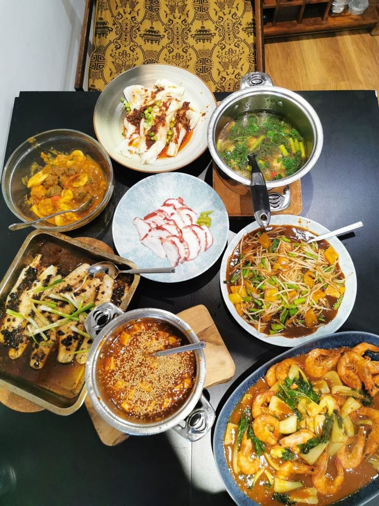 An overhead shot of a black table with eight different dishes of food in various pots, bowls, roasting trays and platters An overhead shot of a black table with eight different dishes of food in various pots, bowls, roasting trays and platters