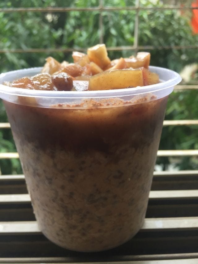 A picture of a cup with oats and apples on top.