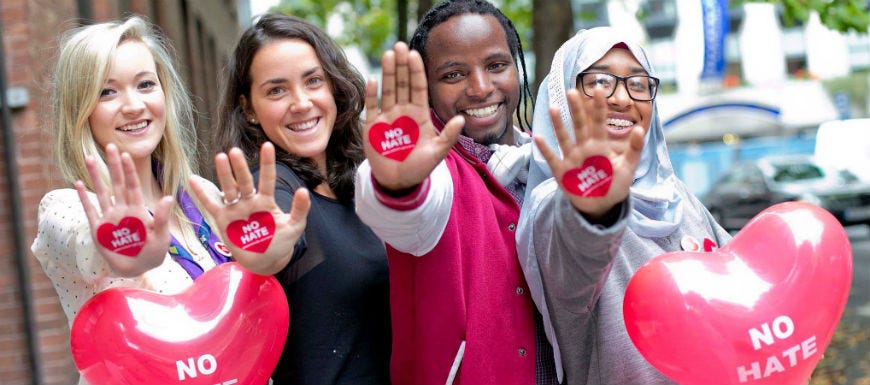 Diverse group of young people holding up hands with "No Hate" heart on them