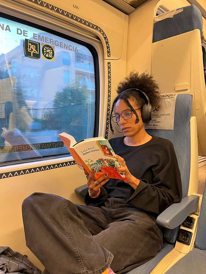 Photo 1: A book on a table beside a pair of glasses, handwritten notes, and small drawings, suggesting a quiet reading and writing moment.Photo 2: A woman reading her own novel on a train, holding the book in natural light.