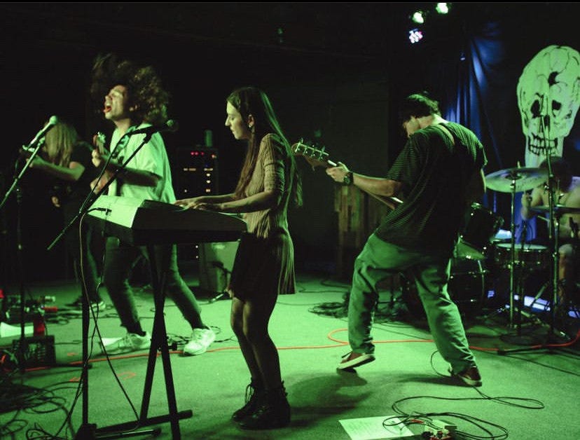 five piece band on stage bathed in green light