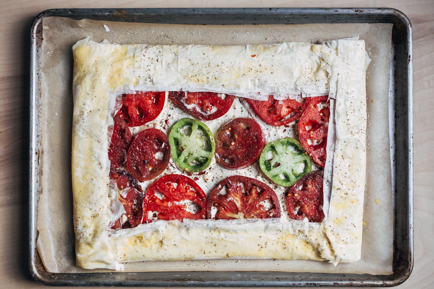 An un-baked tomato tart on a baking sheet